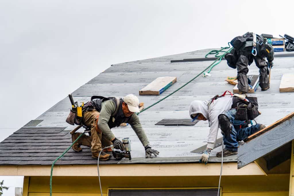 A crew of roof contractors installing shingles