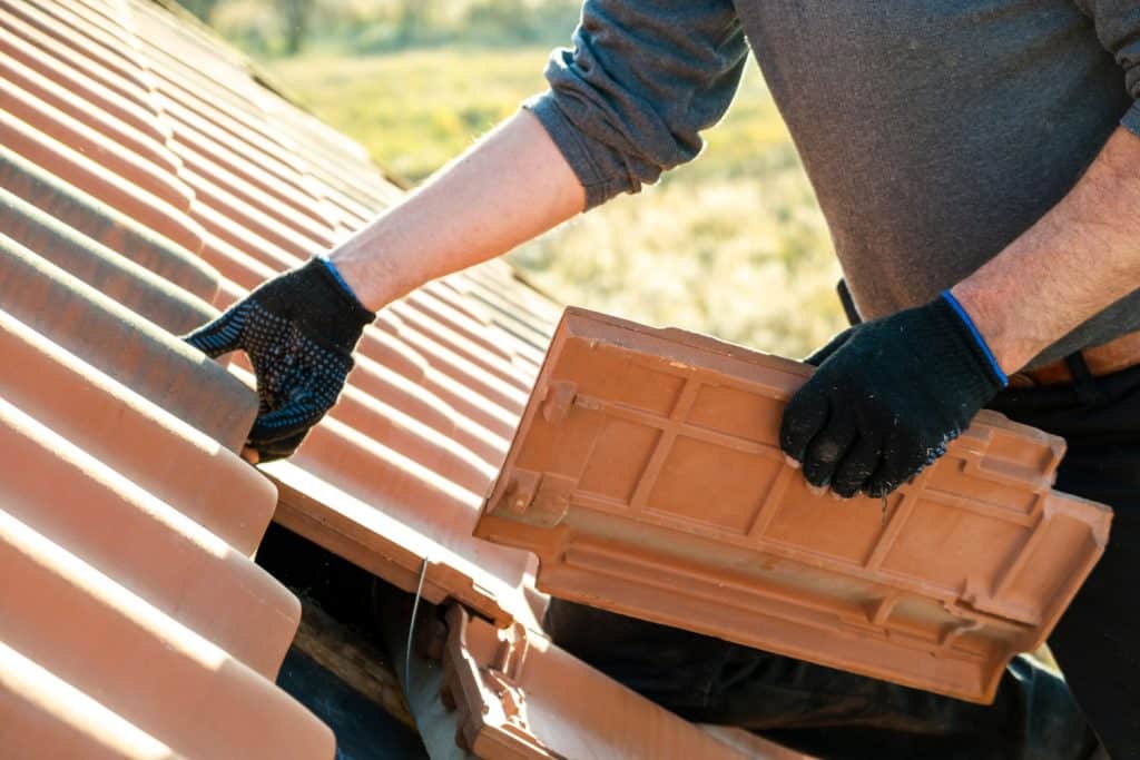 A roofer installing a concrete roof tile
