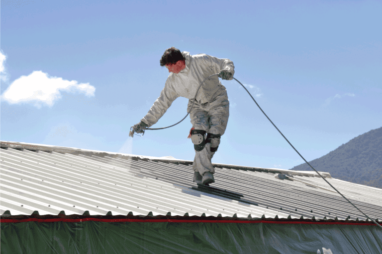 A trademan uses an airless spray to paint the roof of a building. What's The Best Paint For A Roof