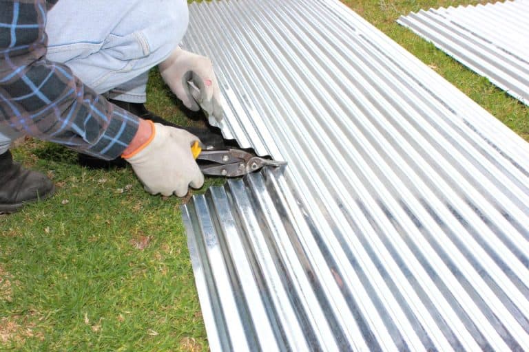 A handyman contractor cutting corrugated iron for roofing repairs, How to Cut Metal Roofing with Tin Snips