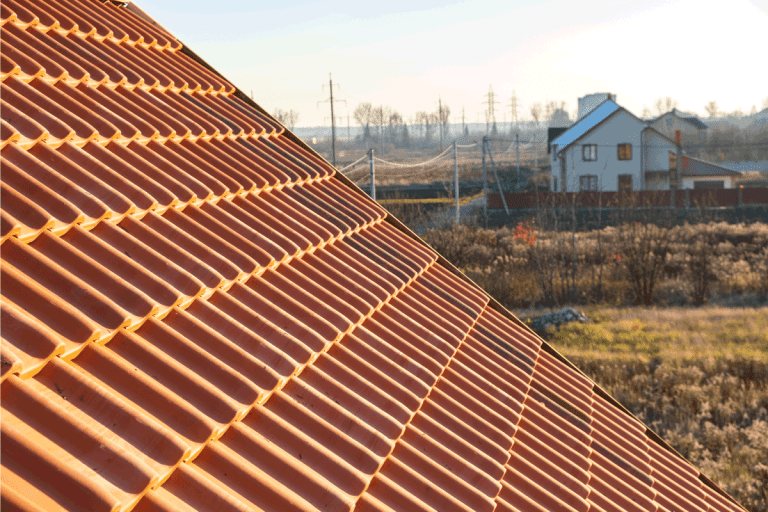 Overlapping rows of yellow ceramic roofing tiles covering residential building roof. Can You Change the Color of Terracotta Roof Tiles