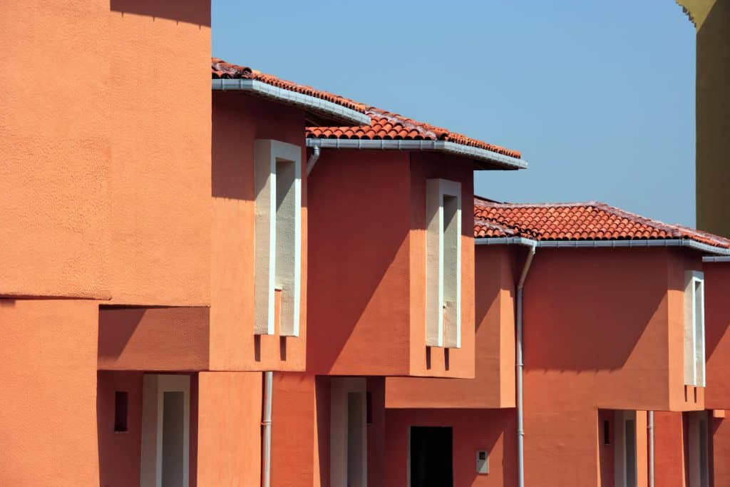 Two story houses in a row with orange stucco siding and red concrete tiles