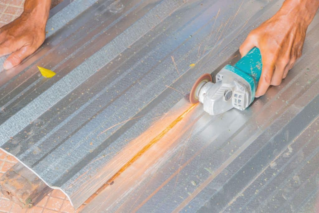 Worker cutting a metal roof sheet using a grinder
