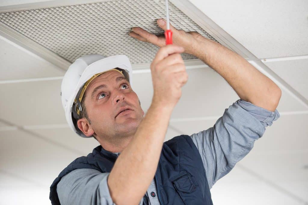 Workman securing screws on ceiling