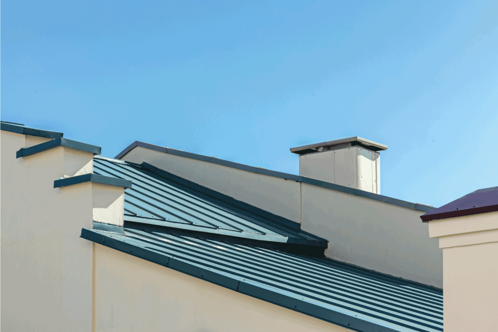 new gray corrugated metal roof with chimney against clear blue sky background