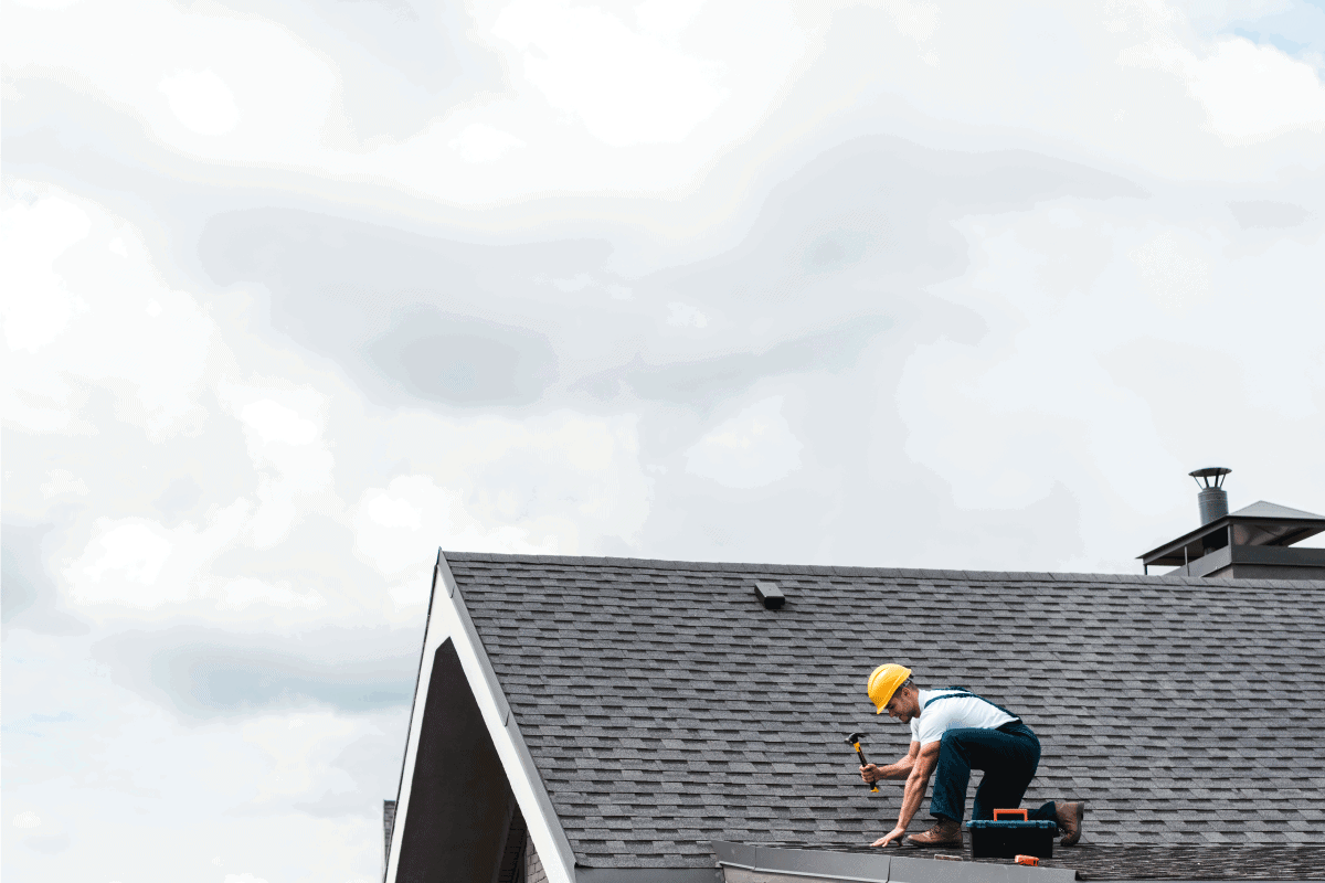 repairman in helmet holding hammer while repairing roof. Is It Normal For Roof To Creak