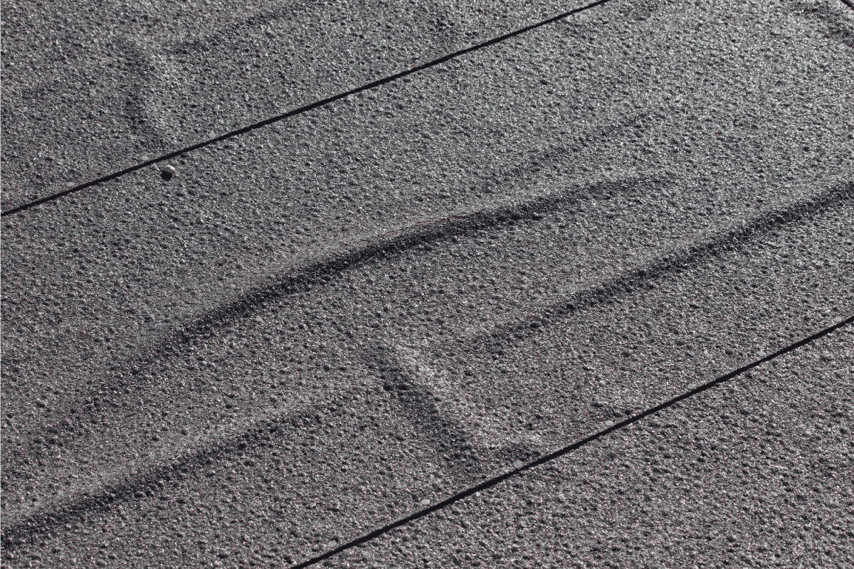 rows of bitumen based roofing felt, which have been laid on the roof of a wooden shed so that they overlap