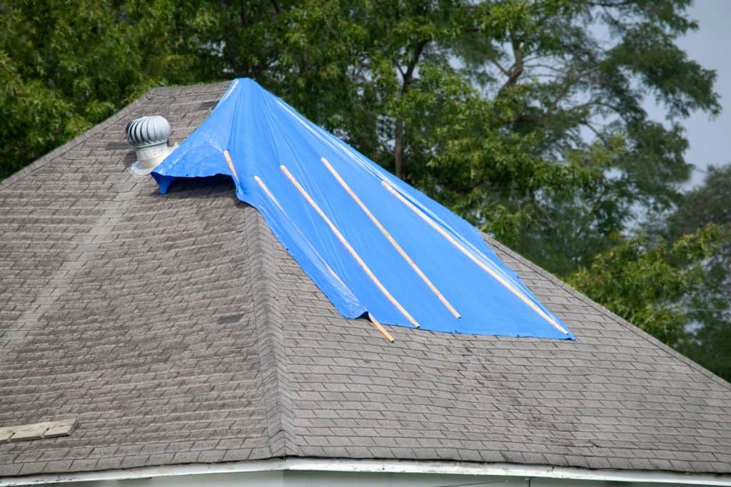 A blue tarp covered top of the roofing shingles due to leaking issues