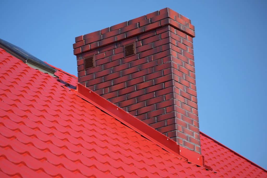 A brick chimney photographed on a house with red roofing