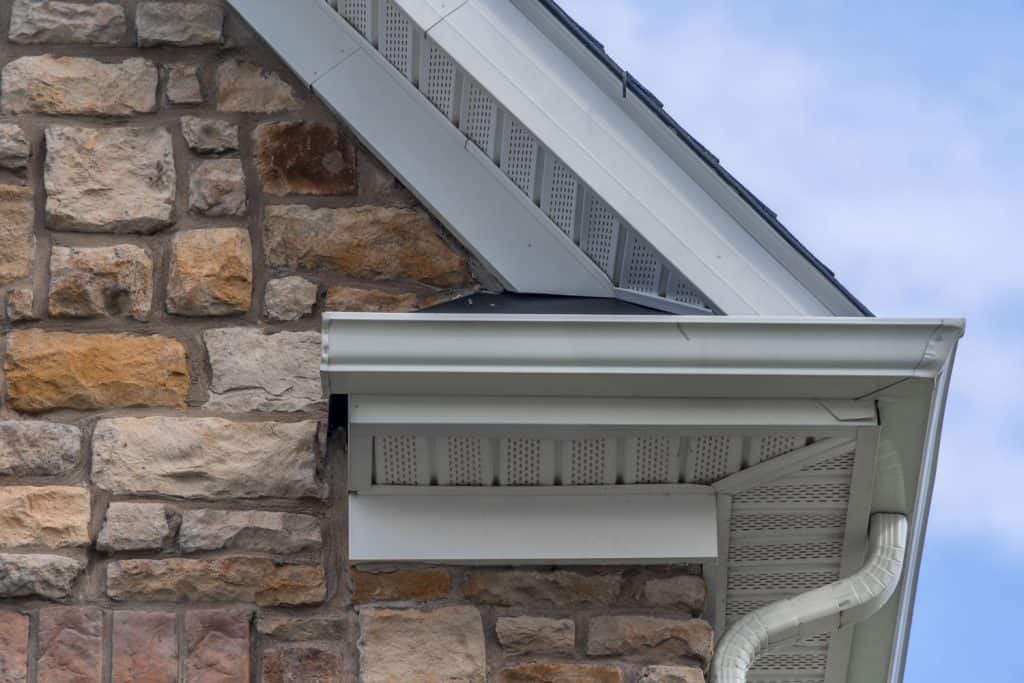 A house with decorative stone sidings and soffit vents and white fascia board