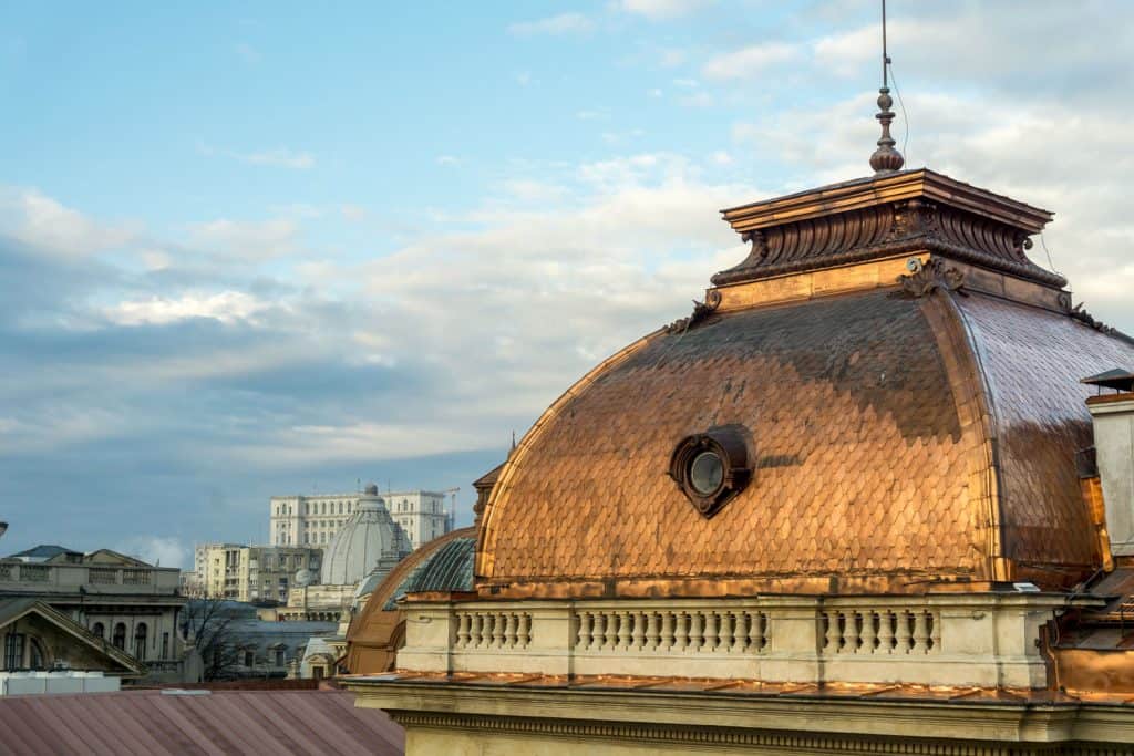 A huge building with copper roofing at a big city