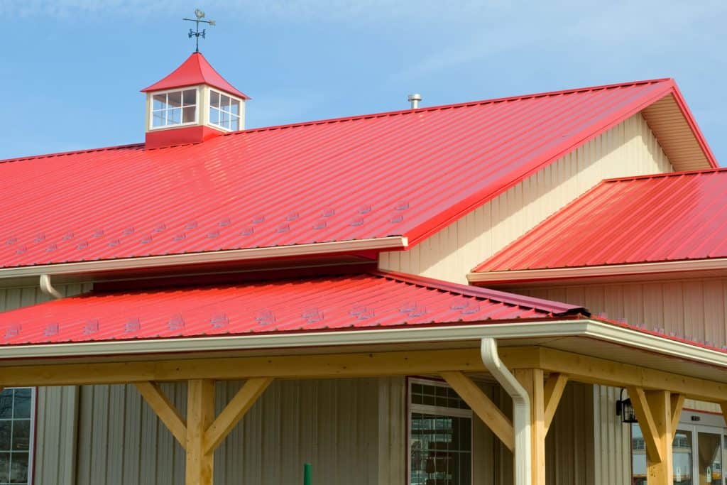 A red roofing of a wooden sidings house with Cupola vent