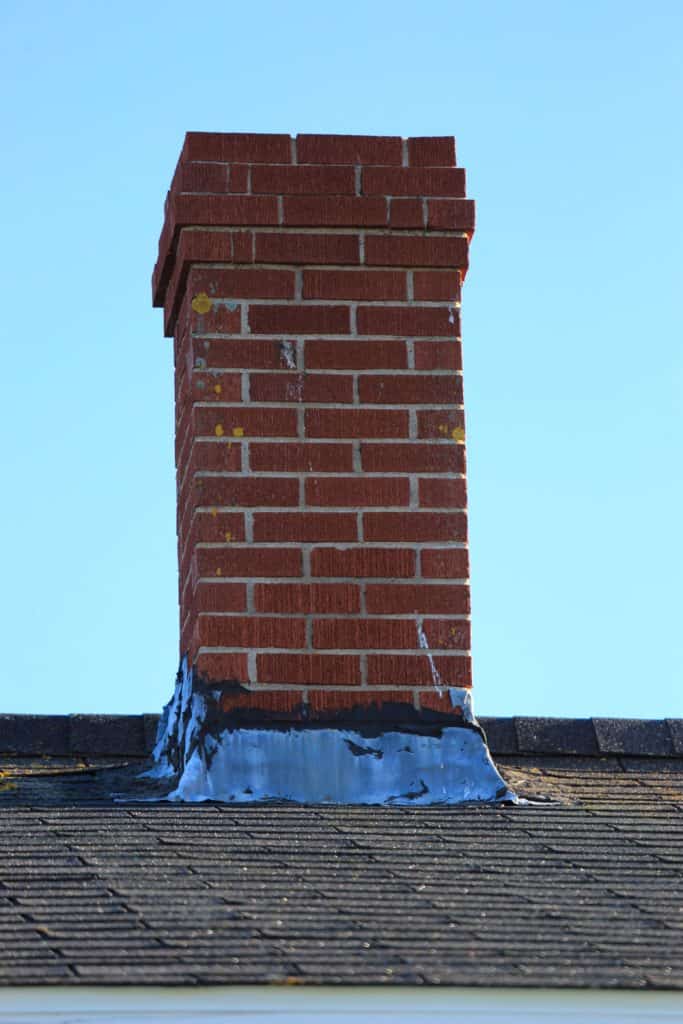 A small brick chimney on a shingle roofing