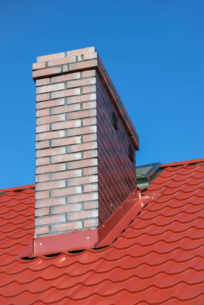 A small brick chimney with metal flashing on the base