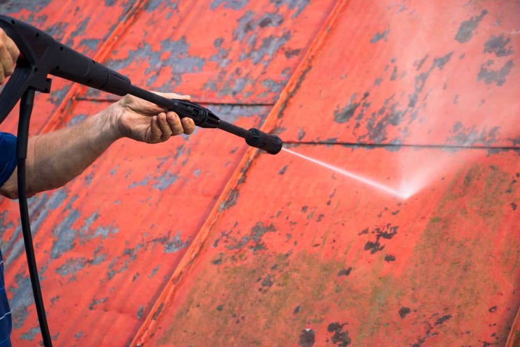 A worker using a power sprayer in removing paint