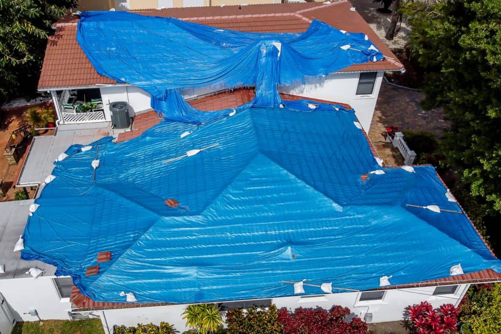 Blue tarp laid out on a mansion for roof replacement