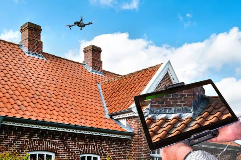 A drone inspecting the roof over the house, How Much Does A Roof Inspection Cost?