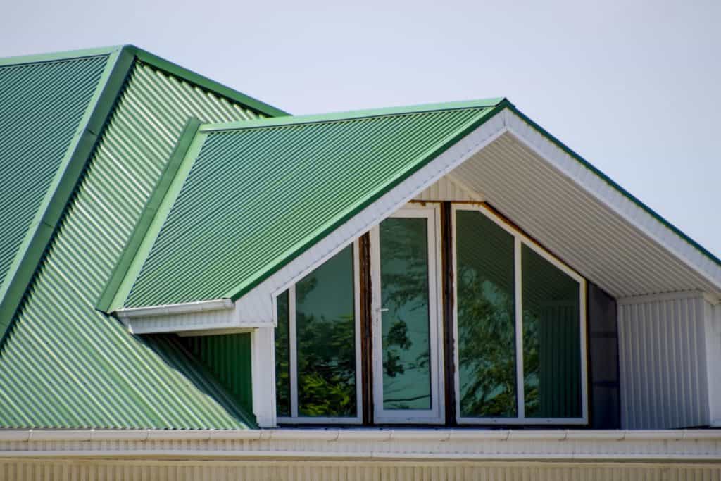 Green roof metal roofing profile with wavy shape on a house with plastic windows