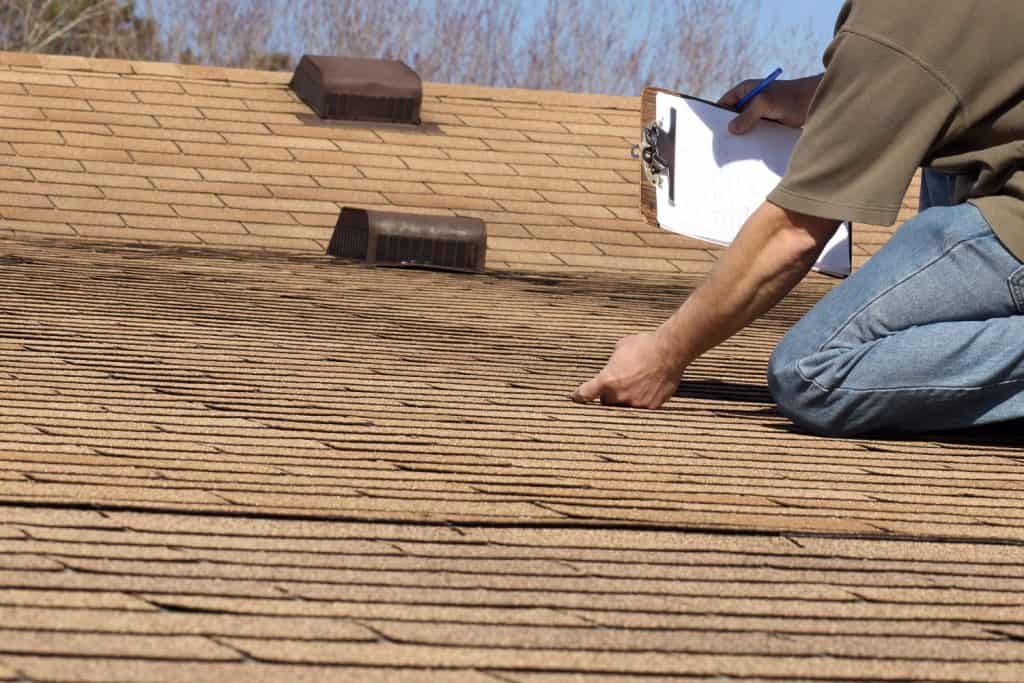 Inspector checking the durability and condition of the roof of a home owner