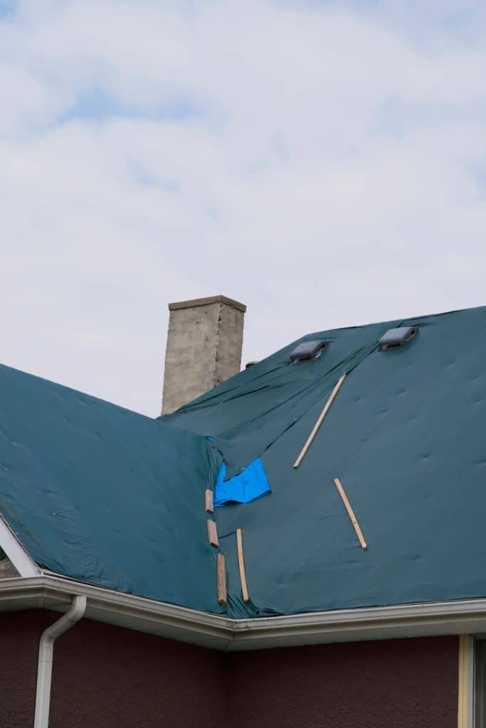 Roof of a house covered with a blue tarp for cover