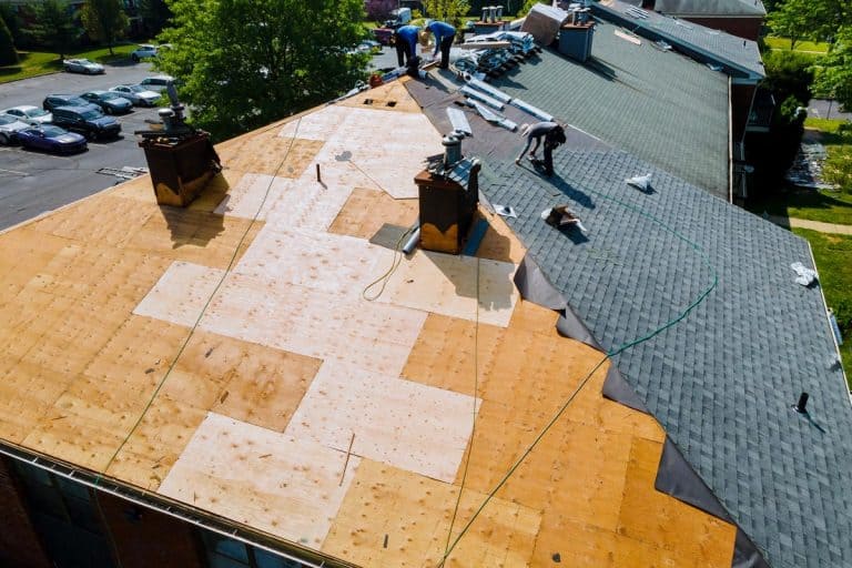 An old roof replacement with new shingles of an apartment building, How often should you replace your roof?