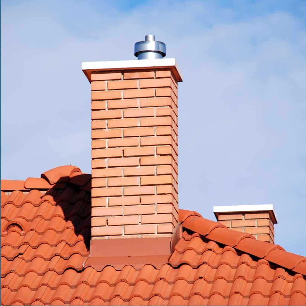 Roof with clay tile roofing and a brick chimney with stainless flashing on the base