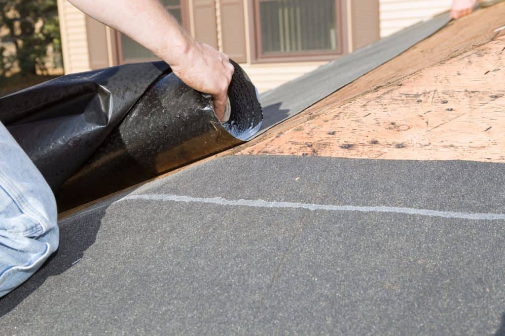 Roofer Unrolling Weather Guard Tar Paper