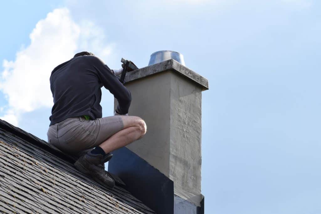 Roofer install the flashing on the chimney for water proofing
