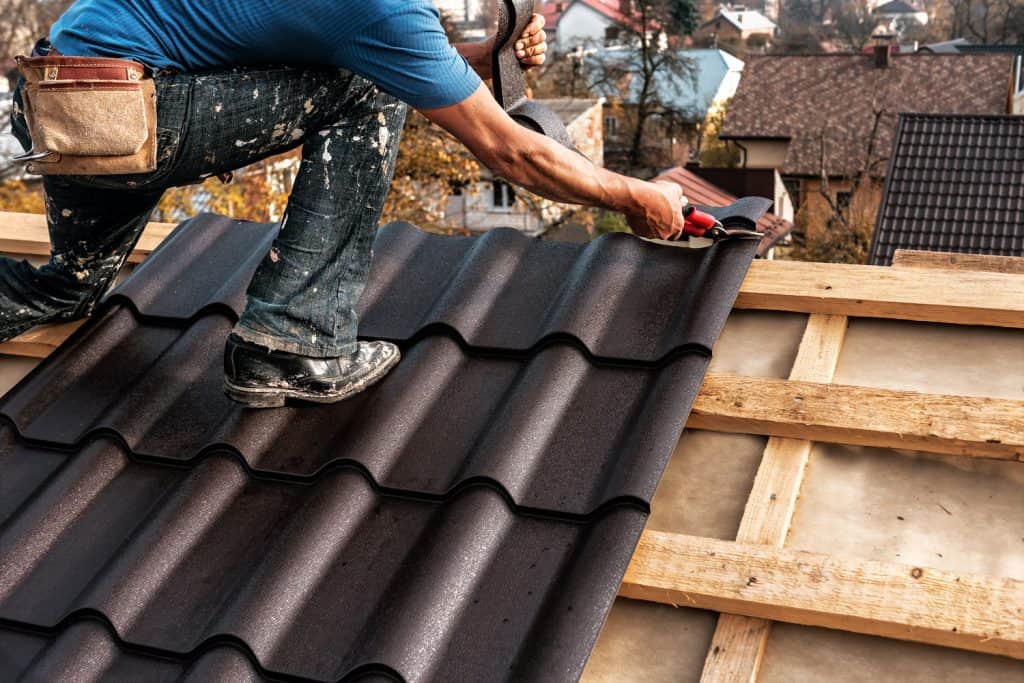 Roofer installing brown metal roof on a house      