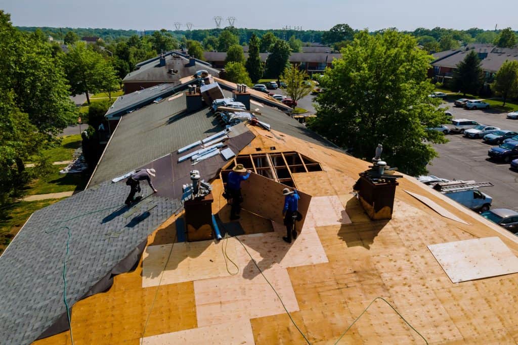 Roofers installing roof sheathings and asphalt shingles for a new reconstructed roof