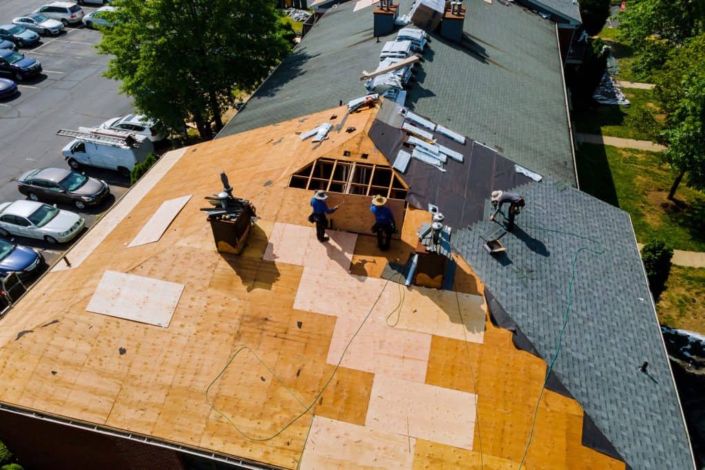 Roofers using brad nailer to install asphalt shingle roofing