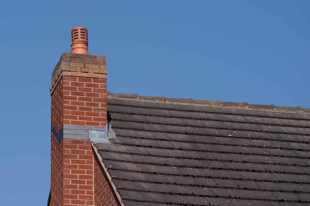 Roofing made from asphalt shingle tile roofing with a brick chimney
