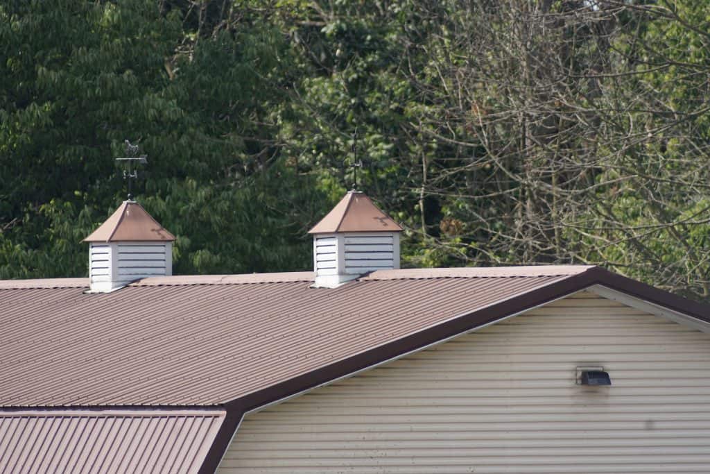 Two white Cupola vents on metal sheet roof house