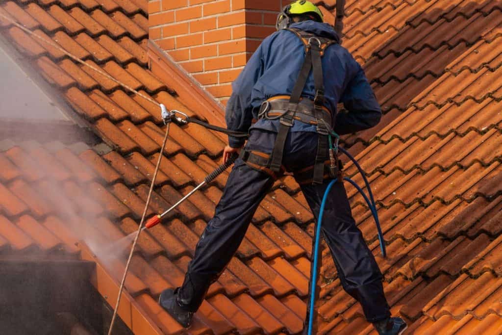 Worker washing the roof with pressurized water