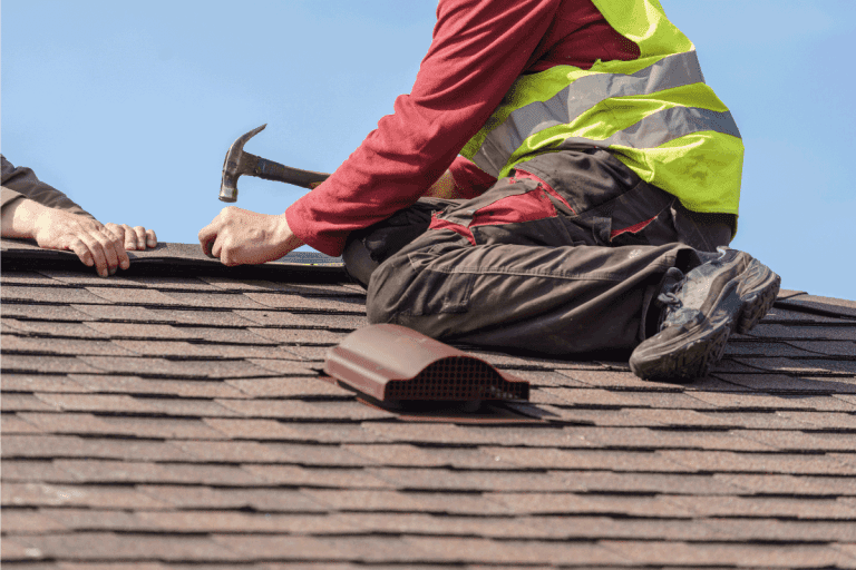 skilled roofer in special work wear with helmet in hands installing asphalt shingle or roof tile on top of new house. What Are The 5 Signs You Need A New Roof