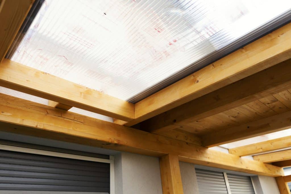 Massive wood beams roof structure covered with transparent polycarbonate sheet, wooden canopy

