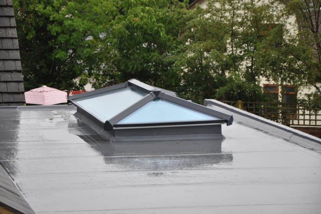 Modern glass roof lantern or light on contemporary grey flat roof in the rain