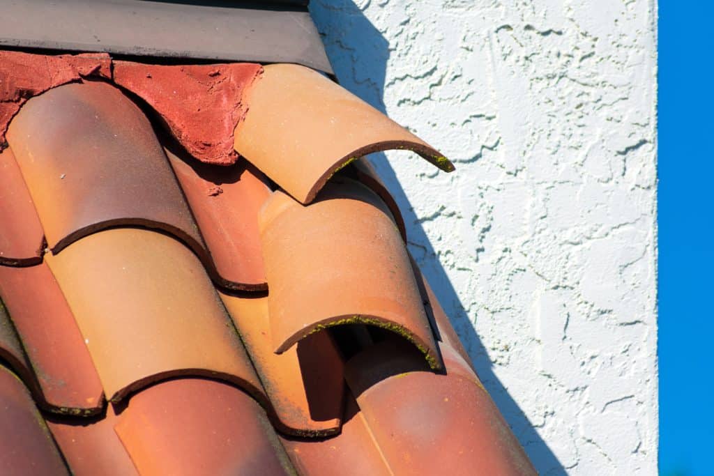 Roof tiles dislodged by strong winds during storm require repair to prevent water leak and interior damage.
