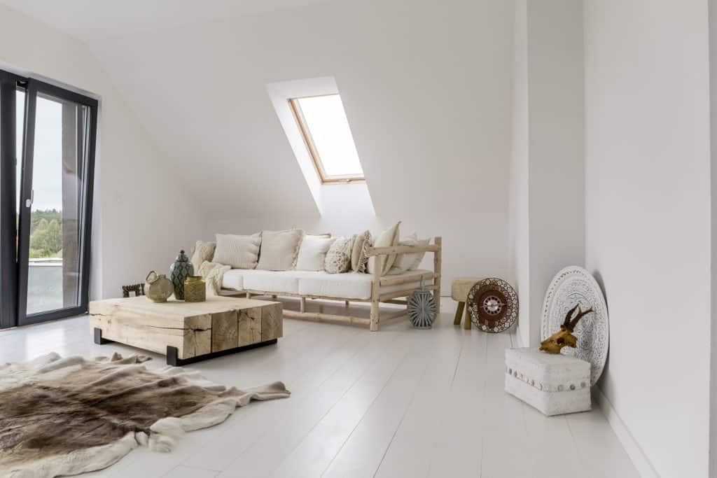 White spacious room with stylish wooden furniture and roof window

